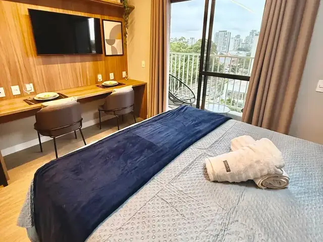 Studio no Alto da Boa Vista com cama arrumada e janela para a cidade