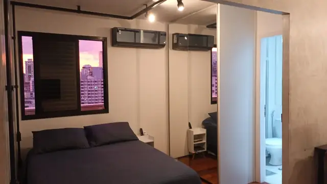 Quarto com cama de casal e janela para a cidade