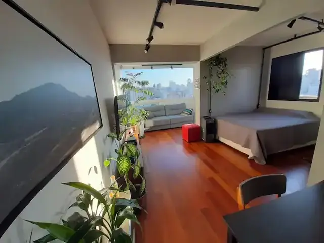Sala com piso de madeira, plantas e vista para a cidade